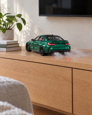 Grüner BMW M3 als Motor Mist-Modellauto mit Nebel aus dem Auspuff auf einem Sideboard im Wohnzimmer
